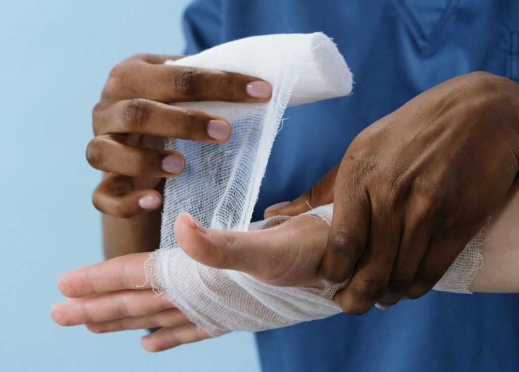 A healthcare professional wrapping a patient's hand with gauze for injury care.